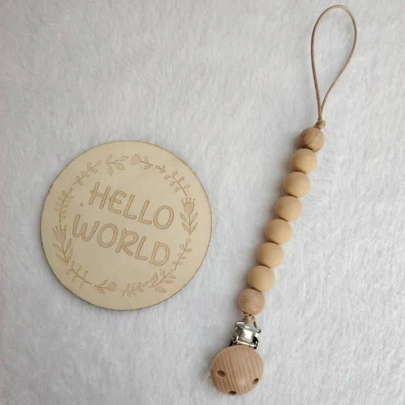 A wooden bead pacifier clip with a silicone teether on a leather cord.
