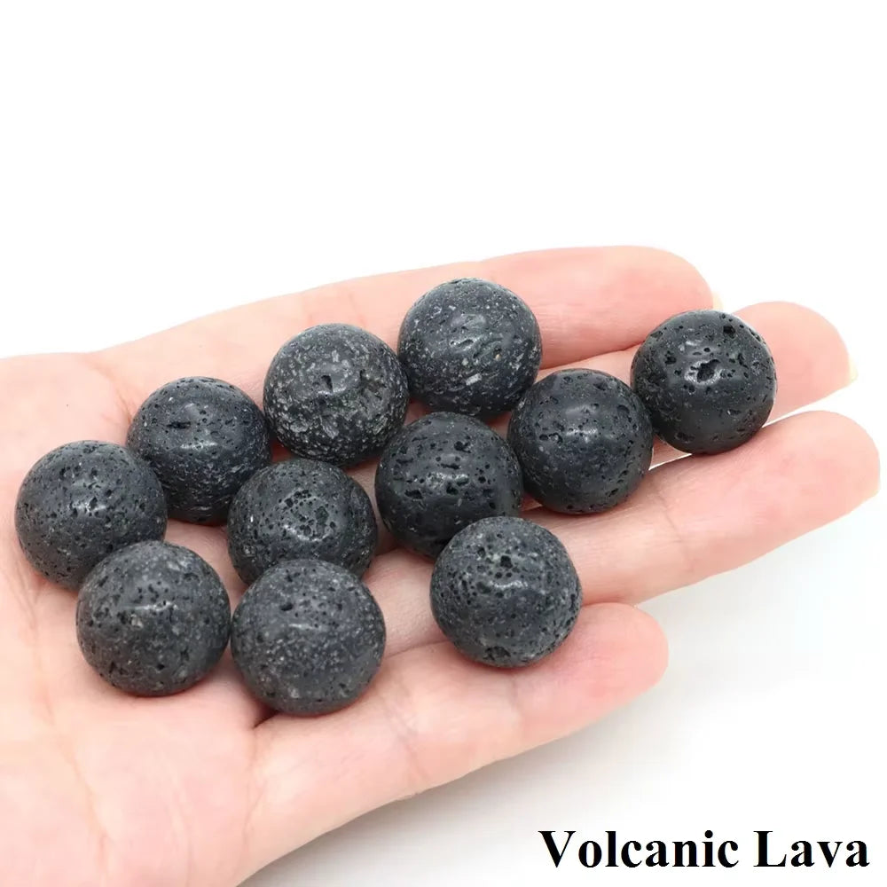 A hand holds several dark volcanic lava crystal spheres.