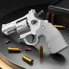 A white spring-powered revolver dart blaster is shown with several gold and black cartridges on a dark surface.