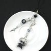Anime-inspired keychain featuring a black silhouette charm and various bead charms on a white plate.
