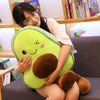 A young woman is holding a bright green avocado plush toy pillow.