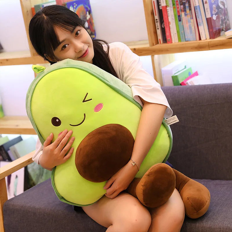 A young woman is holding a bright green avocado plush toy pillow.
