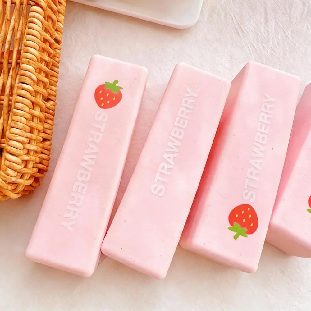 Pink strawberry shaped squishy stress relief toys are displayed next to a woven basket.