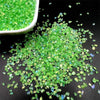 Crushed green glass crystals scattered on a dark surface.