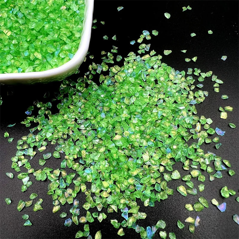 Crushed green glass crystals scattered on a dark surface.