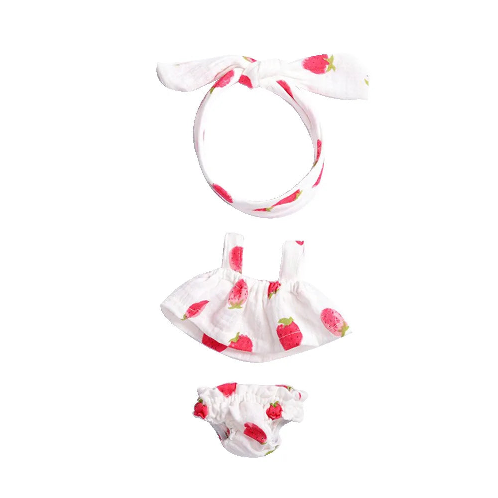 A set of three pink strawberry-themed doll outfits including a bow, a top, and a diaper cover.