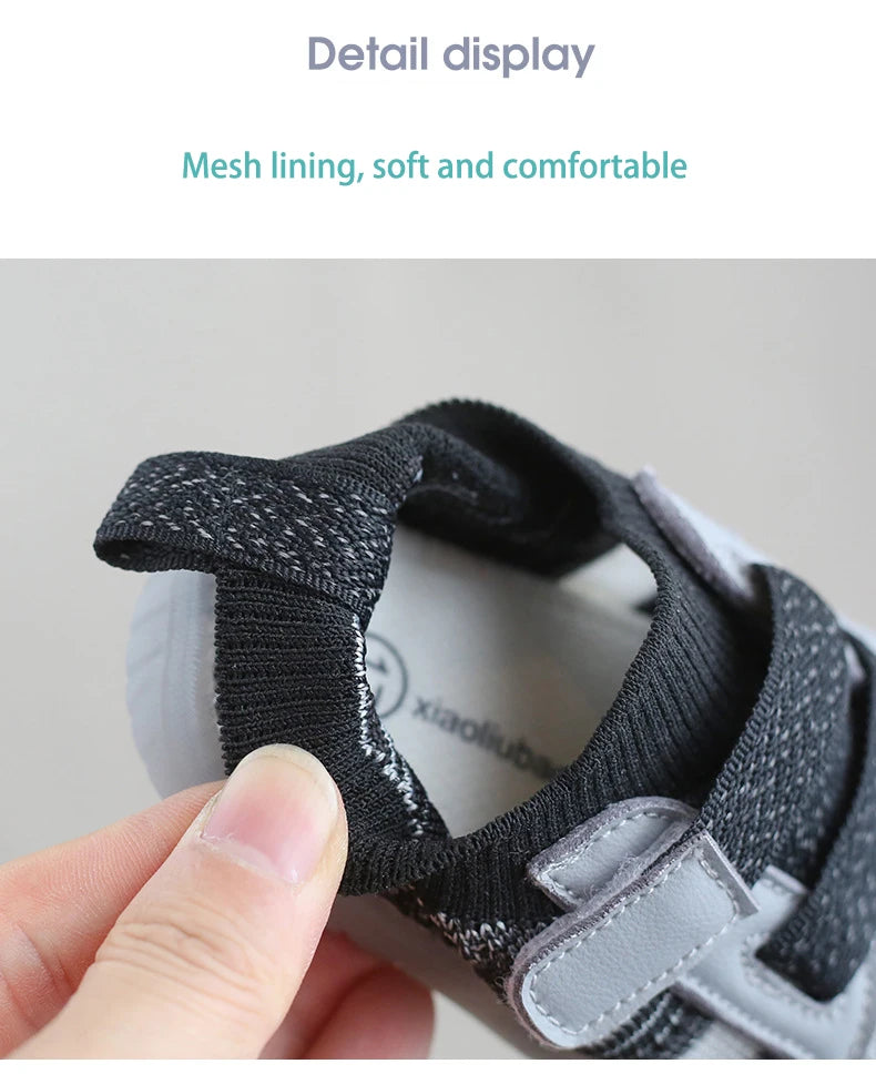 Close-up of a black mesh lined toddler shoe showing the detail display and soft construction.