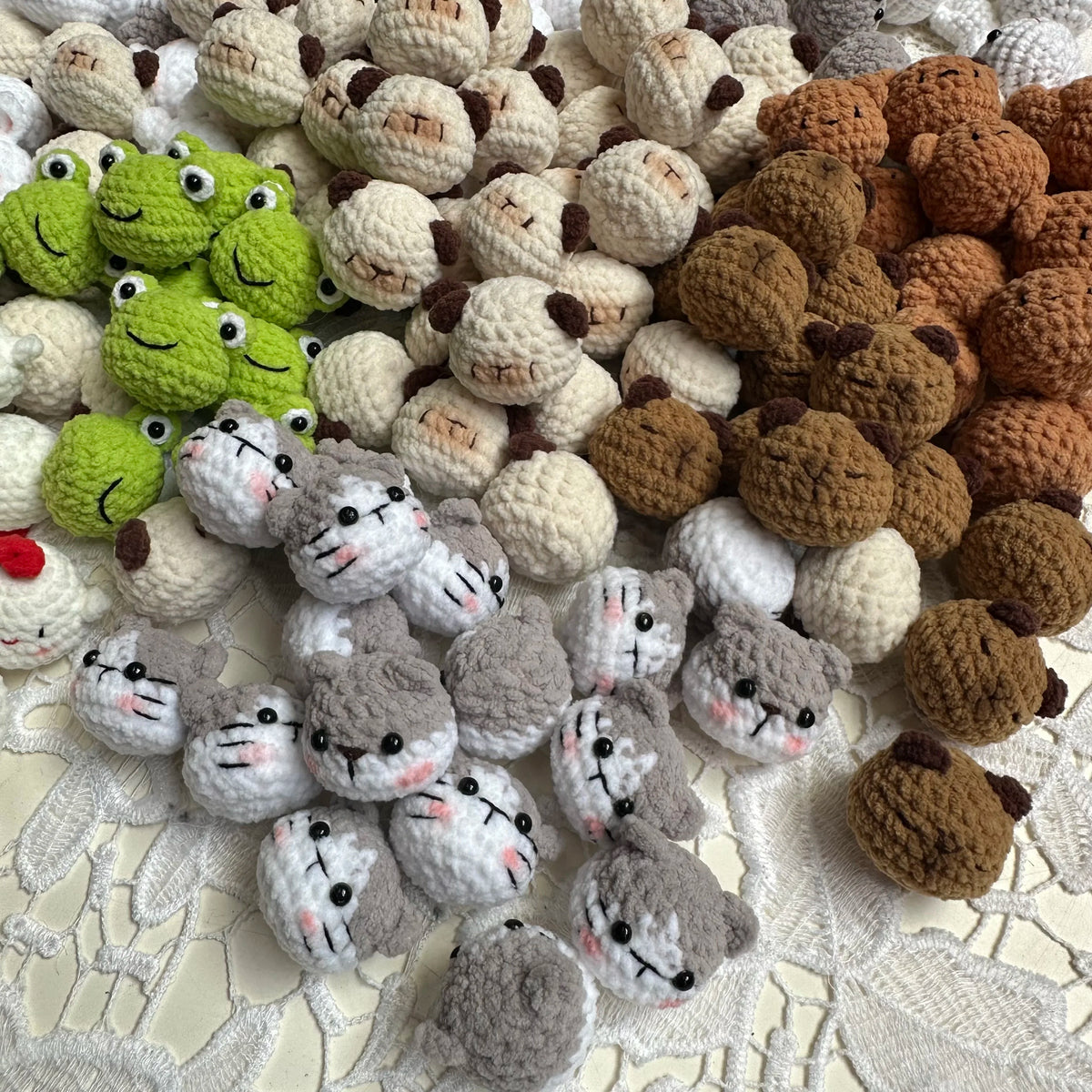 A collection of handcrafted crochet animal keychains in various colors and textures, including rabbits, chicks, cats, and dog