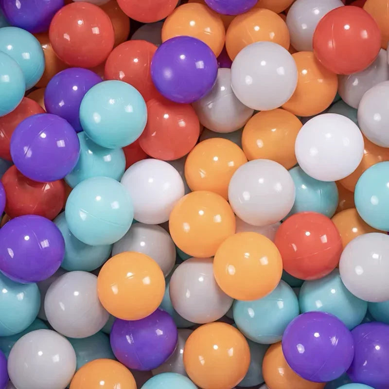 A bulk set of colorful plastic ocean ball pit toys in various shades of orange, purple, and white.