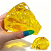 A hand holds a yellow, translucent honey cheese mochi squishy fidget toy against a white background.
