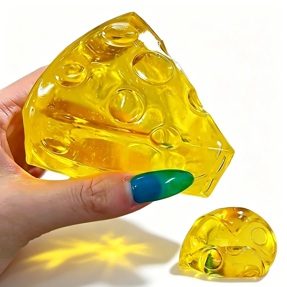 A hand holds a yellow, translucent honey cheese mochi squishy fidget toy against a white background.