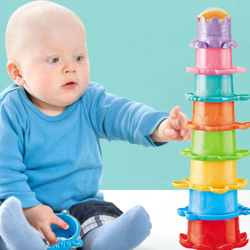 A baby is interacting with a colorful stacking cups toy set featuring floating boats.