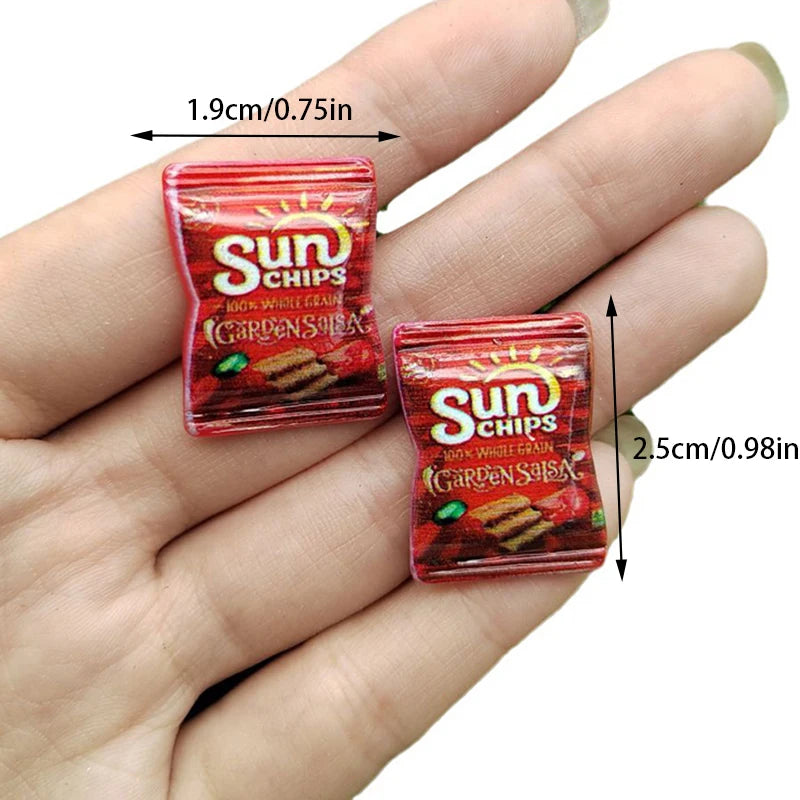 A hand holds a red package of Sun Chips potato chips with dimensions 1.9cm/0.75in.