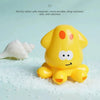 A yellow, rubber duck-shaped bath toy is shown resting on white, granular material.