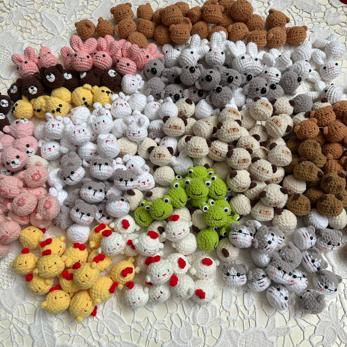A collection of handcrafted crochet animal keychains in various colors including pink, brown, gray, and yellow.