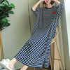 A woman models a navy and white striped short-sleeve lounge dress indoors.