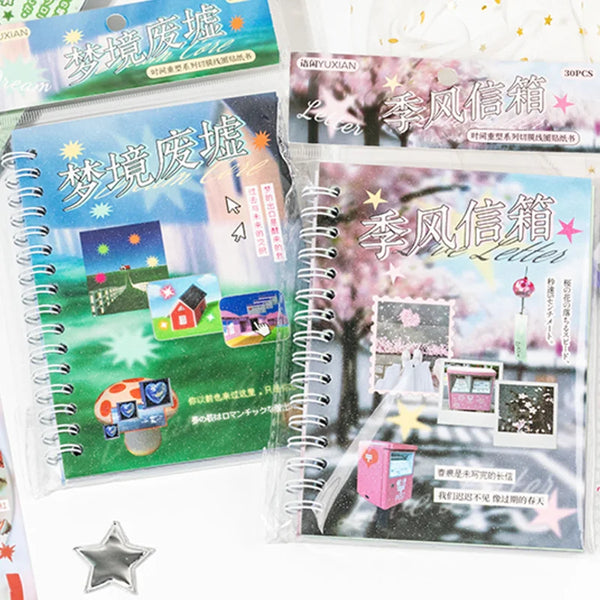 A set of two clear plastic sticker books featuring seasonal letter designs and paper stickers for scrapbooking