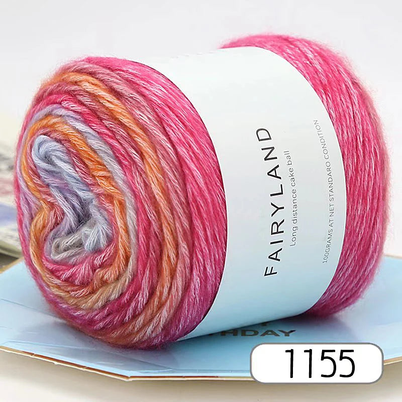A spool of pink and orange gradient rainbow yarn labeled Fairyland for knitting and crochet.