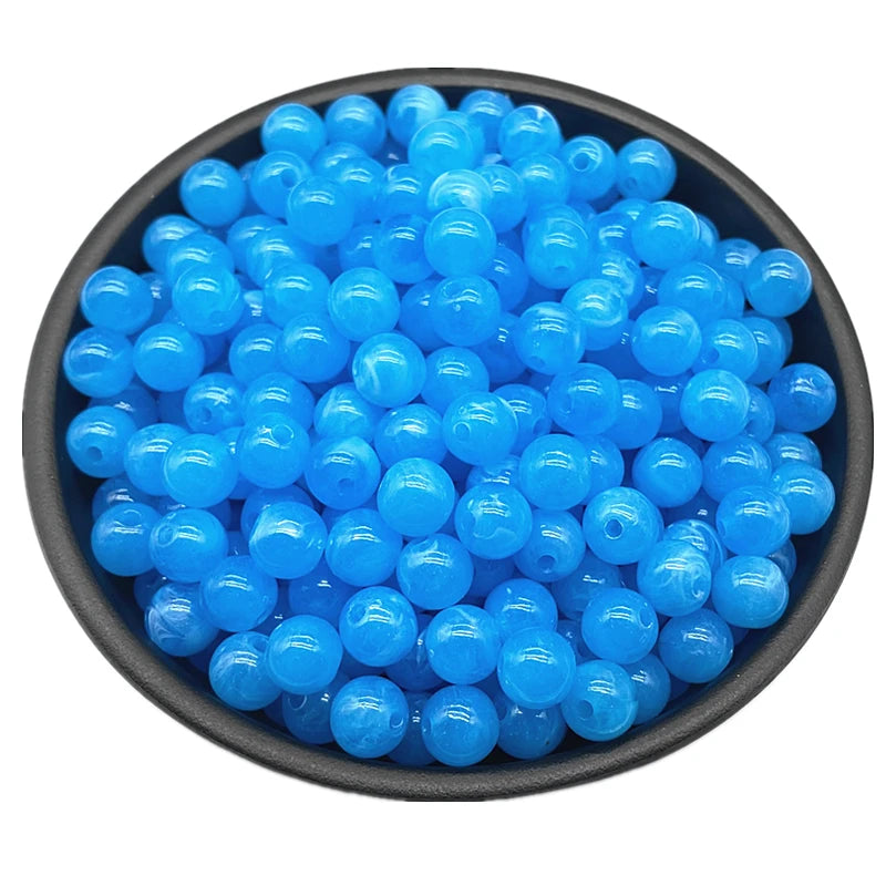 A pile of bright blue acrylic round beads for jewelry making.