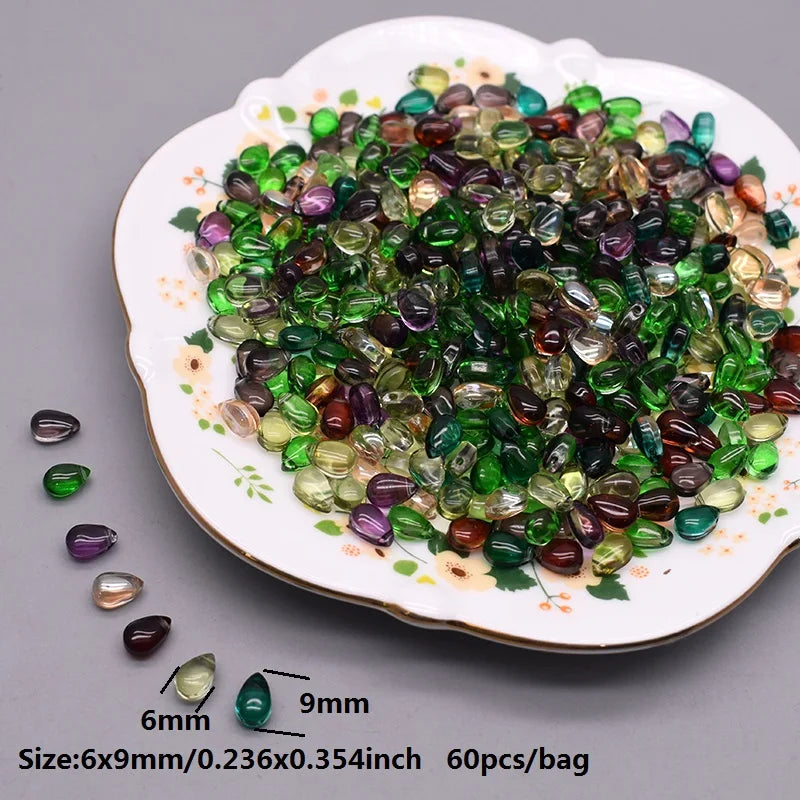A plate filled with green and purple water drop Czech glass beads for jewelry making