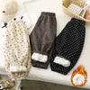 A pair of black fleece-lined pants with white polka dots and a fluffy trim, next to a beige patterned pair.