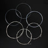 A collection of six silver-plated classical guitar strings with transparent nylon cores arranged in a star pattern.
