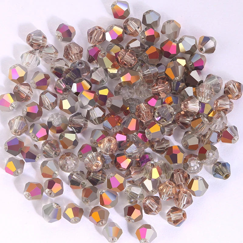 A pile of faceted crystal bicone glass beads in various shades of pink, amber, and clear glass.