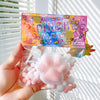 A hand holds a package of cute pink and white cat paw squishy stress relief toys.
