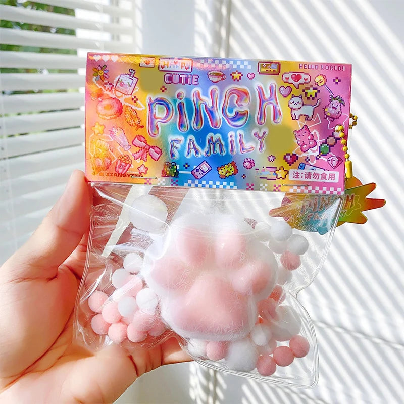 A hand holds a package of cute pink and white cat paw squishy stress relief toys.