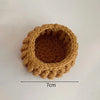 A round, hand-crocheted coaster made of brown yarn with a textured, ruffled edge.