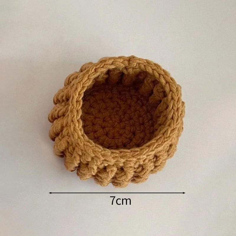 A round, hand-crocheted coaster made of brown yarn with a textured, ruffled edge.