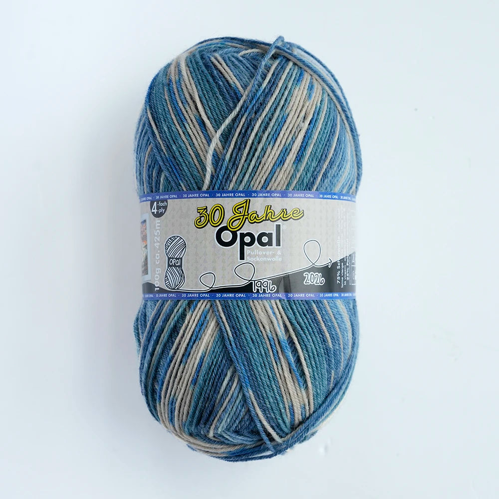 A ball of blue and gray Opal 4-ply sock yarn with a label indicating 30 Jahre Opal.