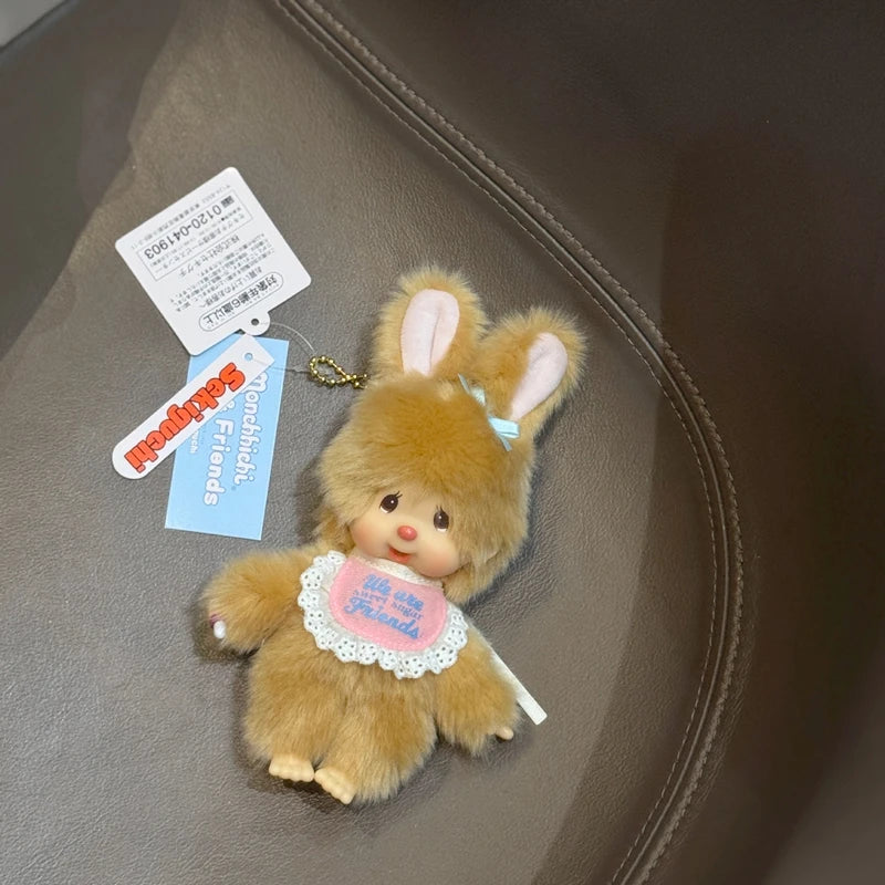 A fluffy brown rabbit plush cartoon keychain charm with pink accents and a tag on a leather surface.