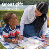 A woman is helping a young boy color on a sheet of paper with jumbo washable crayons outdoors.