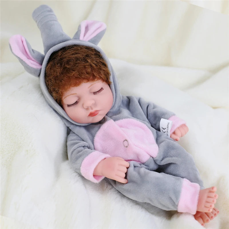 A baby doll wearing a gray and pink cozy winter romper outfit with elf ears lying on white fabric.