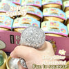A hand holds a silver glitter ball squishy toy with a unicorn theme, demonstrating its squeezable texture.