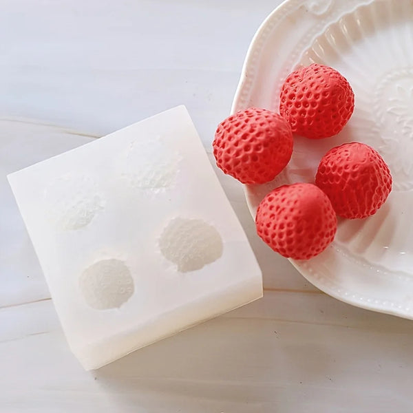 Red silicone spheres and white powder are displayed on a white plate next to a white mold.