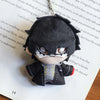A plushie pendant charm of an anime character with black hair and white markings, resting on a piece of paper.