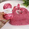 A hand holds a pink satin ribbon yarn labeled Haojing Knitting Yarn, next to a finished pink knitted bag.