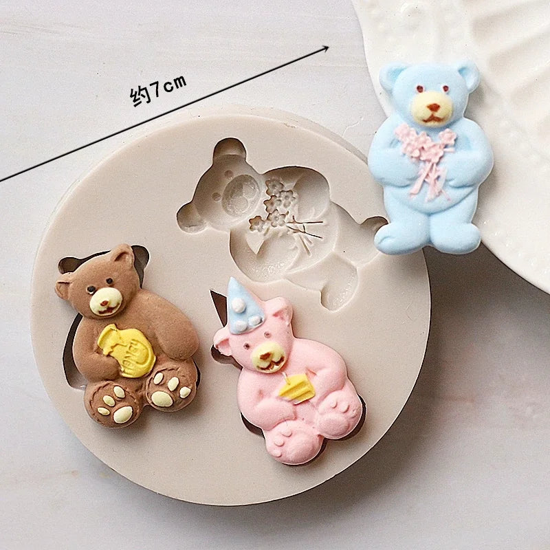 A set of silicone baby-themed cake molds including a teddy bear, a pink unicorn, and a blue bear.