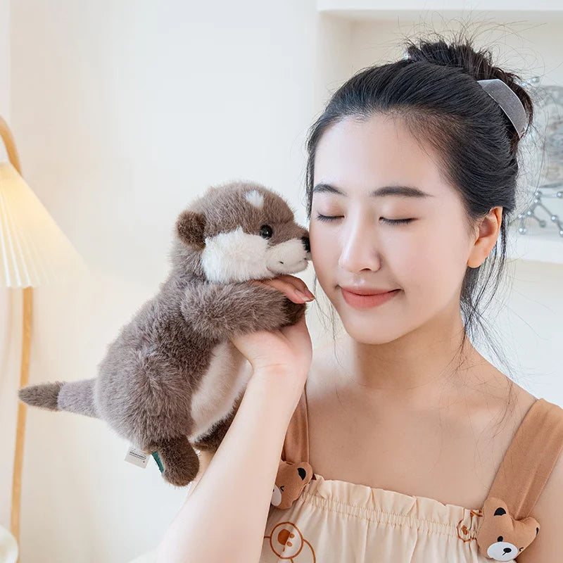 A woman gently holds a brown magnetic otter plush toy against her face.