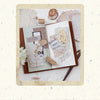 A vintage scrapbook paper combo kit featuring various aged papers, dried flowers, and decorative elements on a brown backgrou