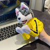 A plush toy of a dog character wearing a yellow outfit and holding a black number one, sitting on a laptop.