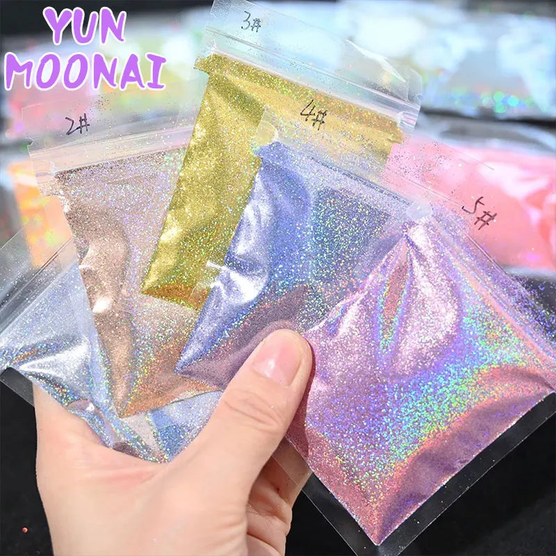 A hand holds several small plastic bags of holographic rainbow nail glitter for DIY nail art