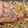 A hand holds a collection of mixed metal charms, including gold and silver, for DIY jewelry making.