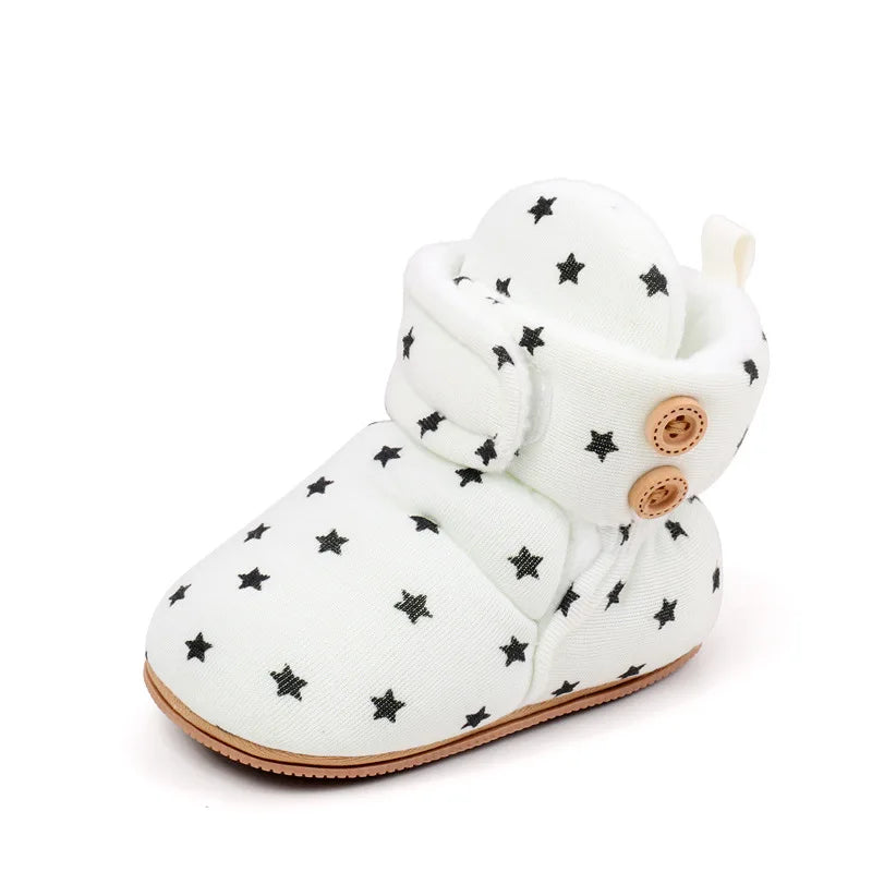 White baby winter snow boots with black star accents and fuzzy ball details