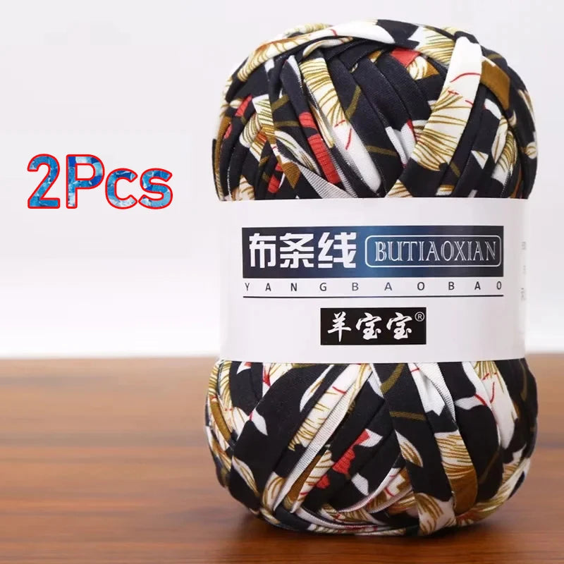 A ball of black and beige patterned soft chunky t-shirt yarn for crochet and knitting, packaged as a 2-pack.