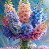 A vibrant bouquet of pink, purple, and blue flowers in a glass vase.