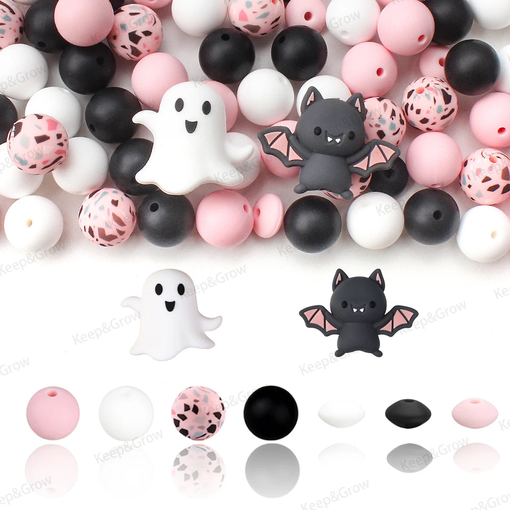 A variety of pink, white, and black silicone craft beads shaped like ghosts and bats are displayed on a white background.