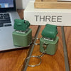 A green duck and frog fidget clicker keychain with a metal ring attached, resting on a wooden surface.